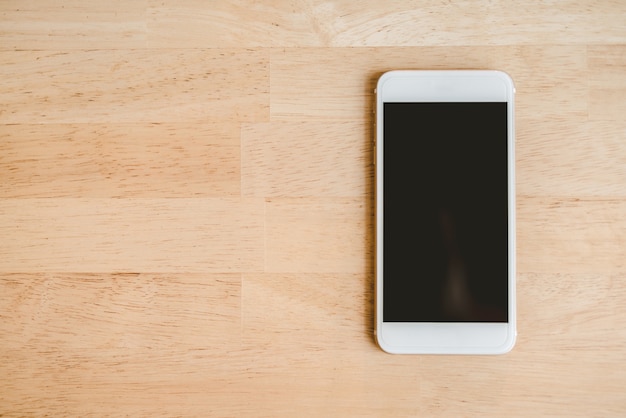 Белый смартфон с изолированным экраном на деревянном столе. - Изображение