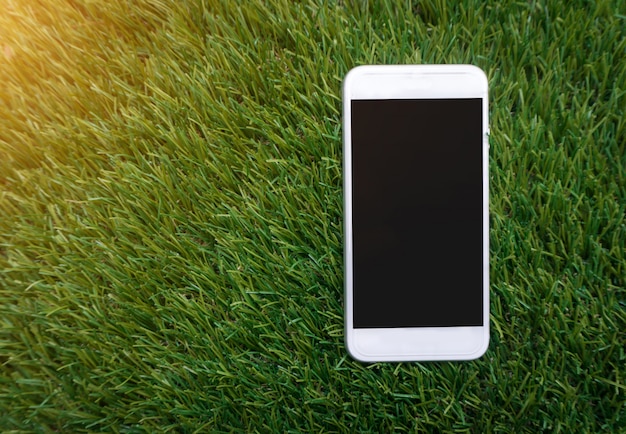 White smartphone with isolated screen on fake grass