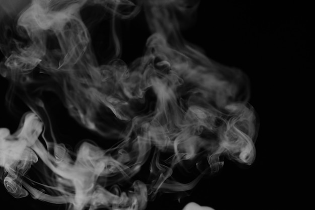 White smoke on a black background. Texture of smoke. Clubs of white smoke on a dark background for overlay