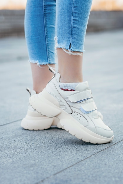 White sneakers on girl legs on the street background