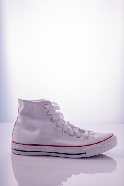 White sneakers with a red stripe on a white background in the reflection