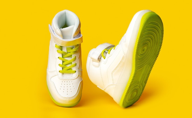 White sneakers with yellow neon laces on yellow background