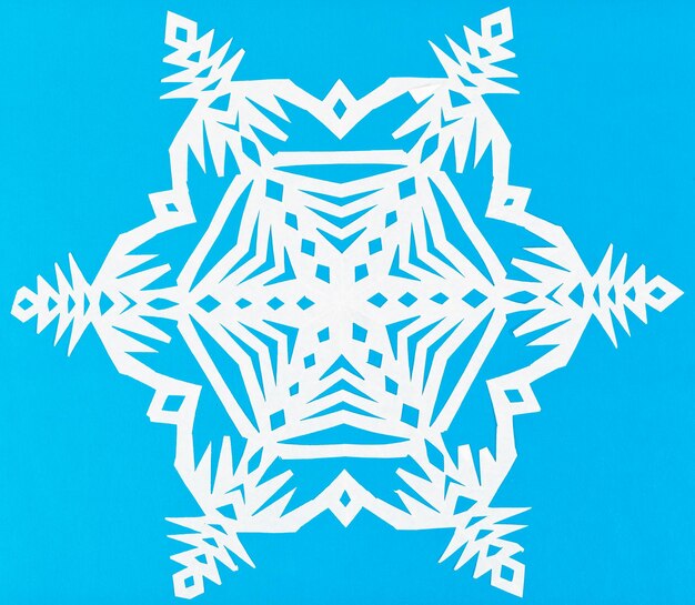 Photo white snowflake on blue paper