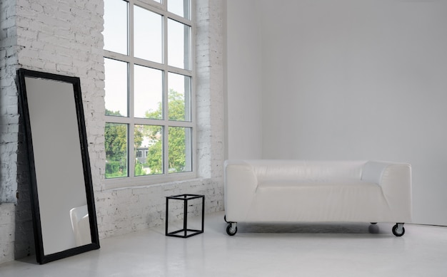 white sofa and large black framed mirror in white room