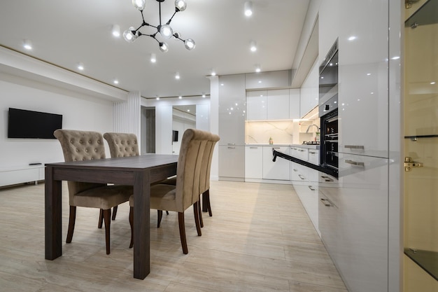 Foto interno bianco della cucina spaziosa con il tavolo e le sedie della sala da pranzo