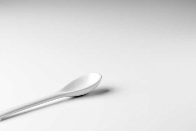 Cucchiaio bianco isolato su una superficie bianca