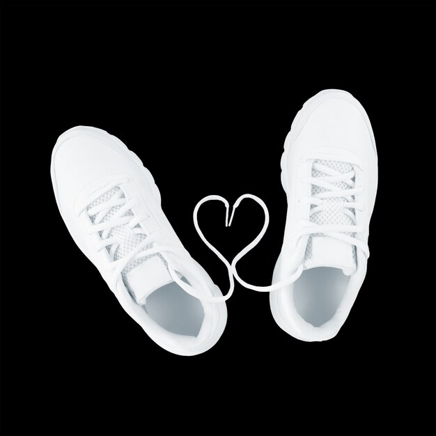 Белая спортивная обувь и форма сердца из шнурков, изолированные на черном