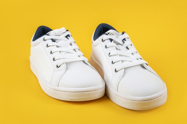 Белые спортивные туфли, кроссовки с шнурки на желтом фоне. Концепция спортивного образа жизни Вид сверху Flat lay