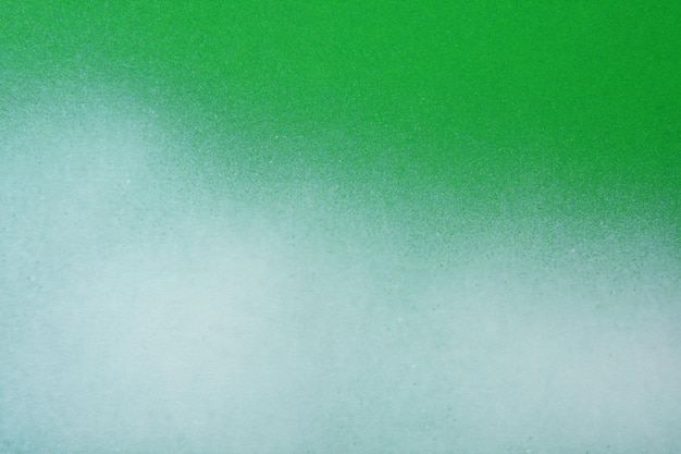 White spray paint on a green colored paper background