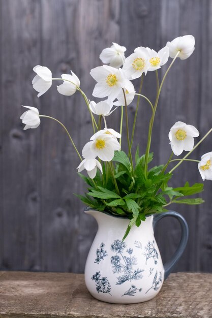 Anemoni primaverili bianchi in vaso su fondo di legno