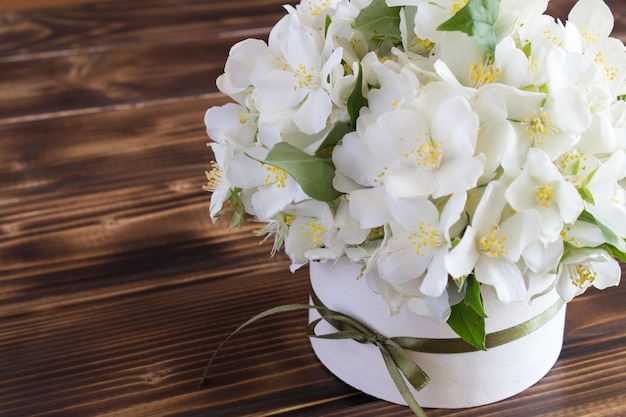 White spring flowers in the box on the rustic wooden background