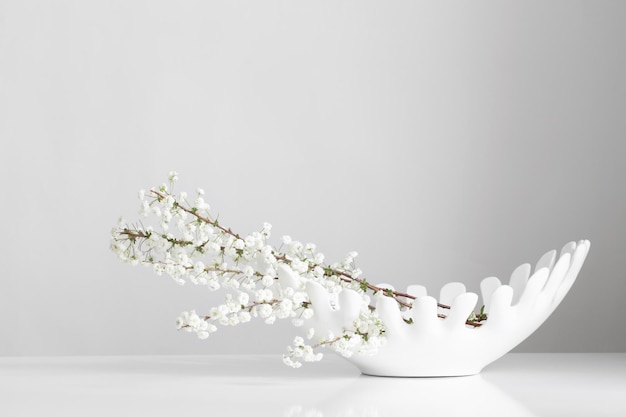 White spring flowers in ceramic white vase on white background