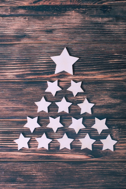 Photo white stars in a shape of christmas tree on a wooden background