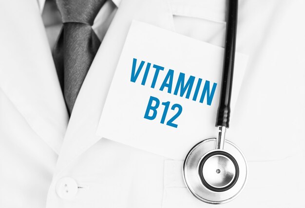 Adesivo bianco con testo vitamina b12 sdraiato sulla veste medica con uno stetoscopio