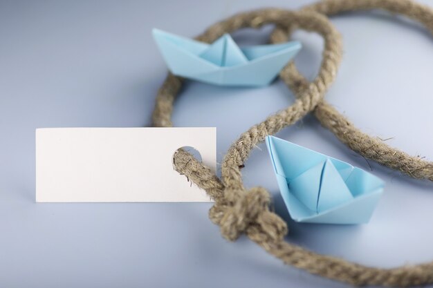 Foto adesivo bianco con corda intrecciata spessa e origami di carta nave