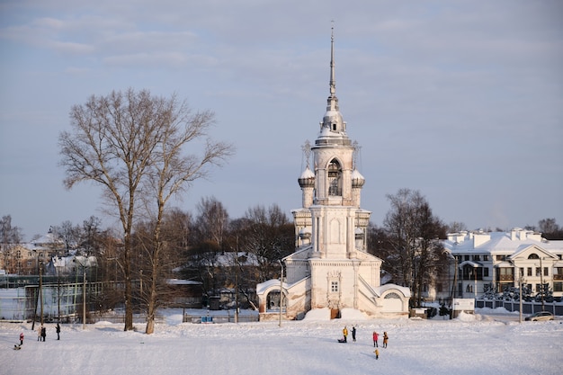 White stone church on the winter embankment on the frozen river