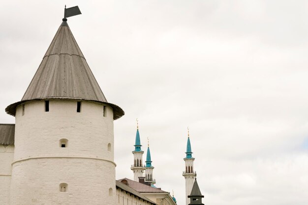 White stone tower with a peaked wooden roof and a beautiful mosque in the background