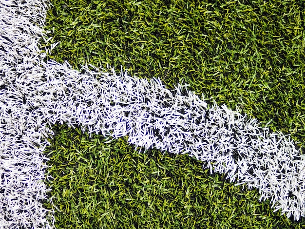 Foto linea d'angolo a strisce bianche sul campo da calcio verde.