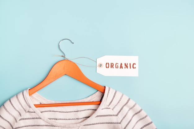 White striped sweatshirt on a hanger and tag with inscription Organic. Eco-friendly clothing