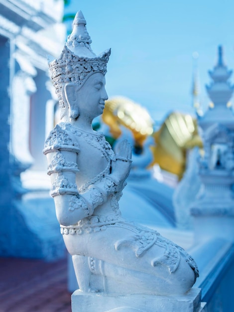 흰색 사리탑과 흰색 조각품으로 둘러싸인 금빛 와불상. 태국 북부 Prae 시에 있는 Wat Pong Sunan 사원.