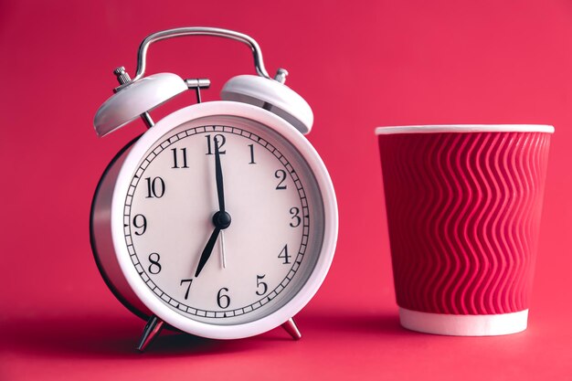 White stylish alarm clock and paper cup morning concept