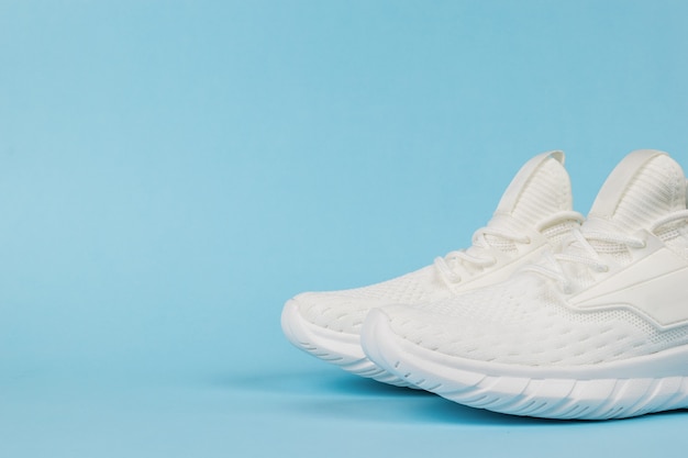 White stylish sports sneakers on a blue background.