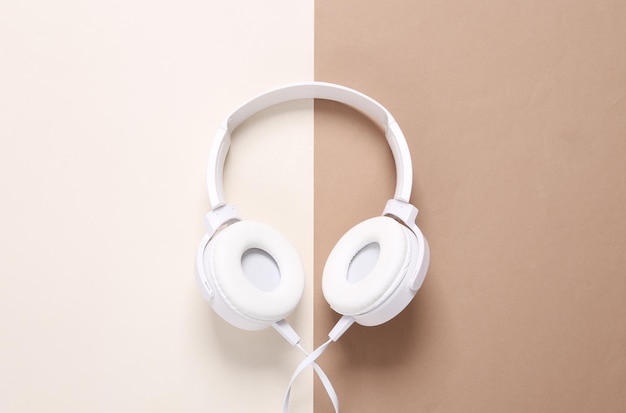 White stylish stereo headphones on brown beige background Minimalistic music still life music lover Top view Flat lay