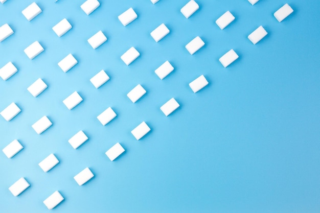 White sugar cubes arranged in diagonal lines on blue background