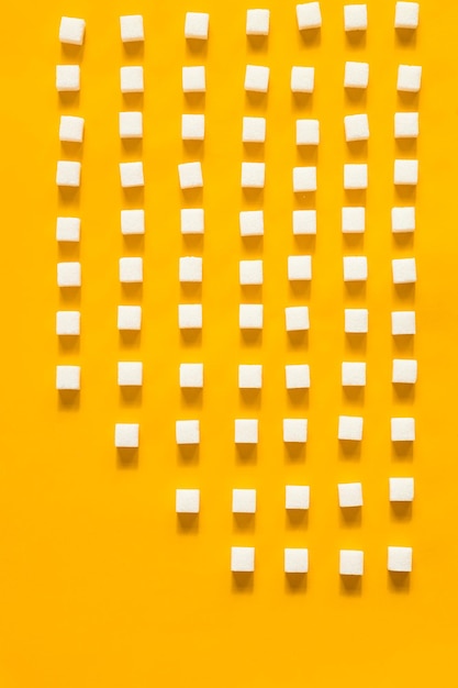 Photo white sugar cubes arranged in diagonal lines on yellow background