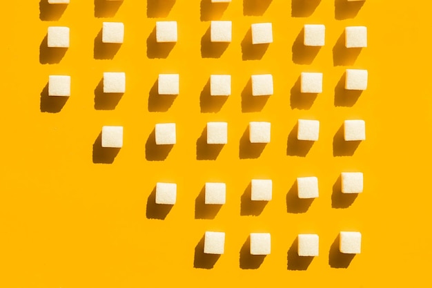 White sugar cubes arranged in diagonal lines on yellow background