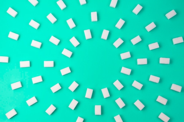 Фото Белые кубики сахара расположены на бирюзовом фоне, вид сверху