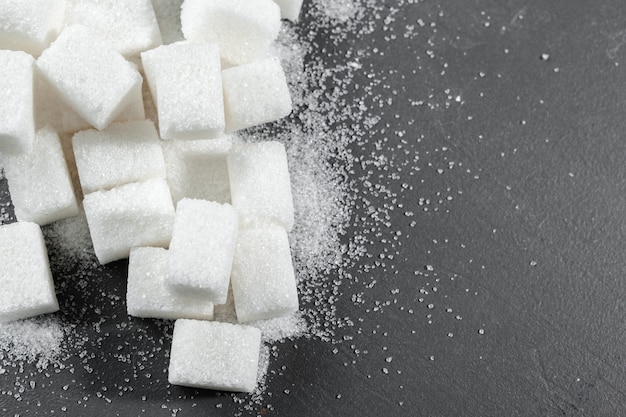 White sugar cubes over black background close up