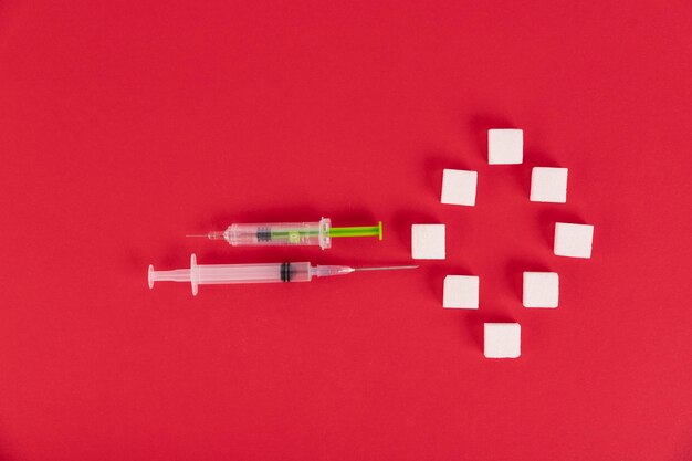 White sugar cubes and syringes on a red background in the form of the number zero. copy the space.