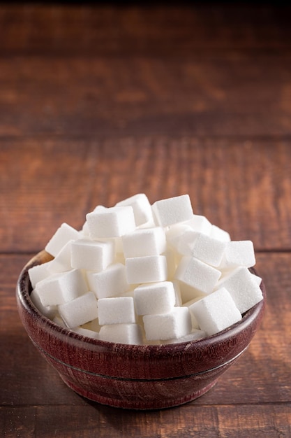 White sugar cubes in wooden bowl