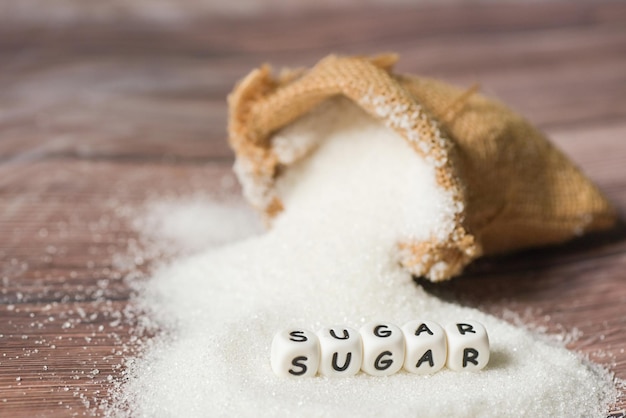 Фото Белый сахар для еды и сладостей десертные конфеты куча сладкого сахара кристаллический гранулированный сахар на мешке и деревянном фоне