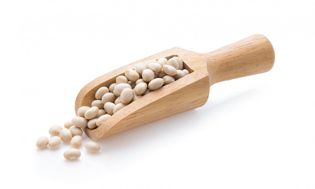 White sugar in wooden spoon on white wall