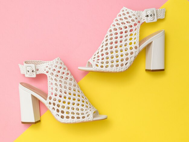 White summer fashion women shoes on pink and yellow surface