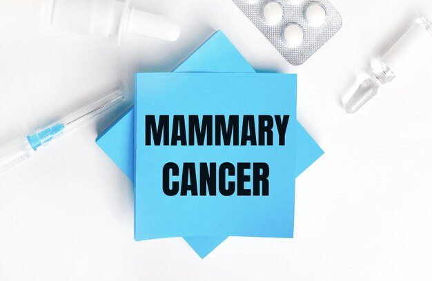 白い表面に、注射器、アンプル、錠剤、薬瓶、水色のステッカーにMAMMARYCANCERの刻印があります