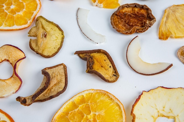 A white surface with oranges, dried fruit, and a slice of orange.