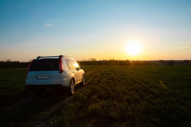 日没のフィールド ロードで白い suv 車