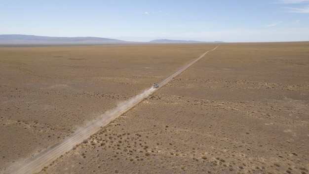Foto un suv bianco sta guidando velocemente su un drone su una strada polverosa.