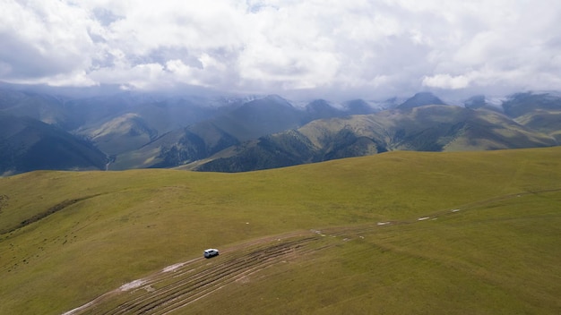 A white suv rides in the mountains through fields