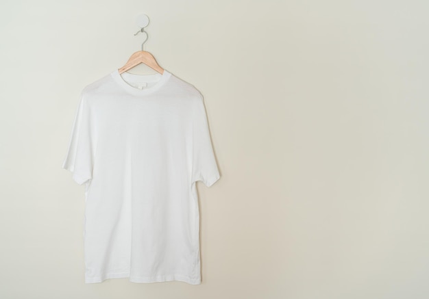 사진 벽에 나무 옷걸이가 달린 흰색 티셔츠