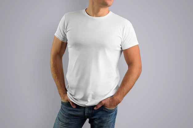 white T-shirt on a young muscular guy isolated on a gray wall.