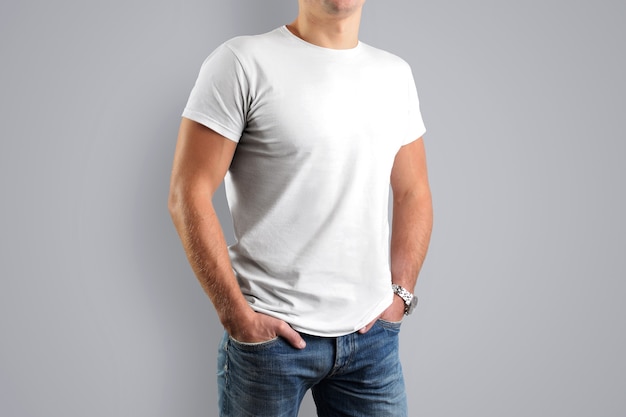 white T-shirts. A young athletic man is isolated on a gray wall.