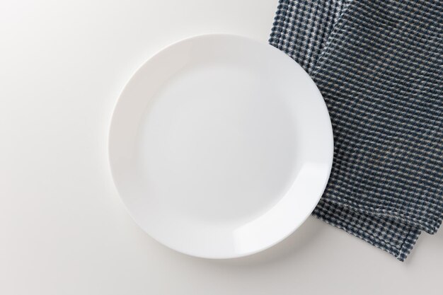 The white table had a white empty plate over the tablecloth. Place for placing text.