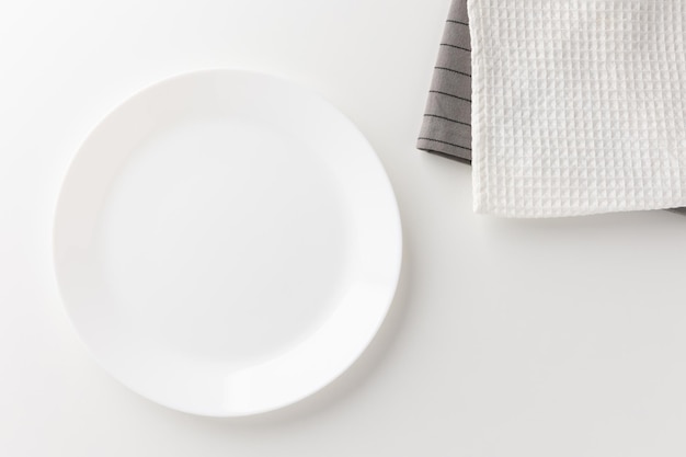 The white table had a white empty plate over the tablecloth. Place for placing text.