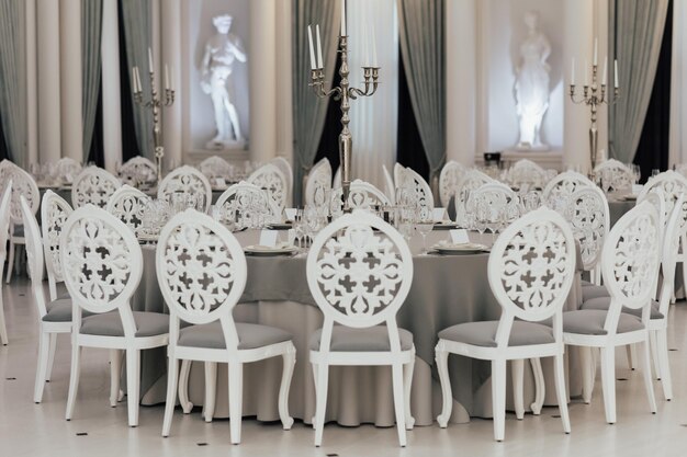 A white table with chairs in a restaurant with a statue in the background