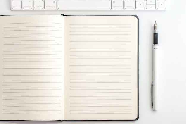 white table with notepad, keyboard and fountain pen. view from above
