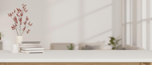 A white tabletop with books a coffee mug and a flower vase against a blurred modern living room